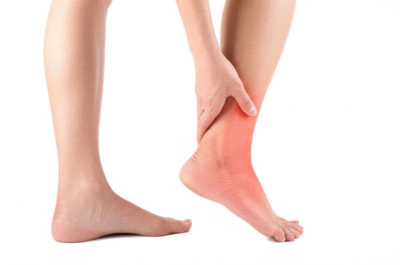 Person holding their achilles tendon area experiencing pain